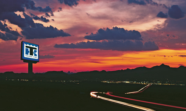 Photo at twilight of a Thermo King dealer sign lit up against the sunset and mountains.