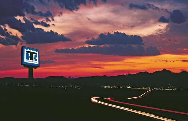 Photo at twilight of a Thermo King dealer sign lit up against the sunset and mountains.									